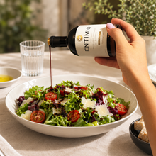 Entimio balsamic vinegar poured over a salad with tomatoes and Parmesan